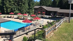 A pool area with a fenced deck, red umbrellas, and lounge chairs. - Mara Spring Lodges - Suite 2 (Mara)