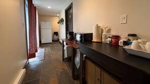 A narrow hallway leading to a kitchen with a dark countertop, a refrigerator, and a sink. - Mara Spring Lodges - Suite 2 (Mara)