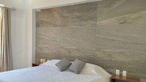 Un dormitorio moderno con una cama grande, un ventilador de techo y una pared con textura.