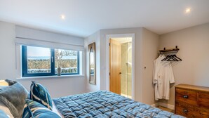 A bedroom with a bed, a window with a view, a wooden dresser, and a walk-in closet. - Moorgate Lodge - UK47742 (Kelbrook)