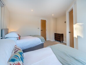 A bedroom with two beds, a wooden wardrobe, and a door.