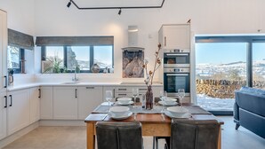 A modern kitchen with a dining area, large windows, and a view of the countryside. - Moorgate Lodge - UK47742 (Kelbrook)