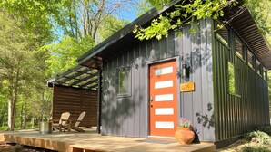 Eine rustikale Holzhütte mit einer Holzterrasse, einer Veranda und einer Tür mit der Aufschrift 'The Betty'.