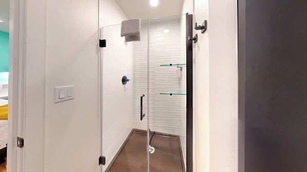 A modern bathroom with a glass shower enclosure, a towel rack, and a visible toilet paper holder.