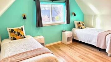 Une chambre avec deux lits, une fenêtre avec des rideaux, une table de chevet et une commode.