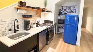 Una cocina compacta con un lavamanos, estufa y un refrigerador azul.