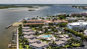 A coastal hotel with multiple buildings, a swimming pool, and a marina with boats. - Discover the perfect getaway at Villa De Marco East, (Marco Island)