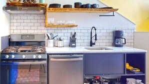 A compact kitchen with a stove, oven, and dishwasher, a sink, and a coffee maker. - Courtyard View at The Commons 24 (Seaside)