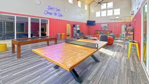 Un espacio interior amplio con mesa de ping pong, asientos y un letrero de neón.