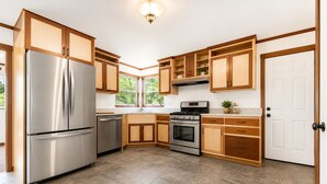 Une cuisine moderne dotée d’appareils électroménagers en acier inoxydable, de meubles en bois et d’une grande fenêtre.