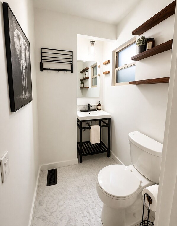A compact bathroom with a white toilet, a black vanity, a mirror, and a hexagonal tile floor. - Sequoia Sanctuary•Hot Tub•Private Hilltop Escape (Three Rivers)