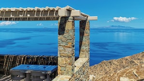 A stone pergola with a table and chairs overlooking a body of water. - AGADA Folegandros (Folegandros)