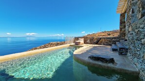 A stone pool with clear water, a beige lounge chair, and a stone wall. - AGADA Folegandros (Folegandros)