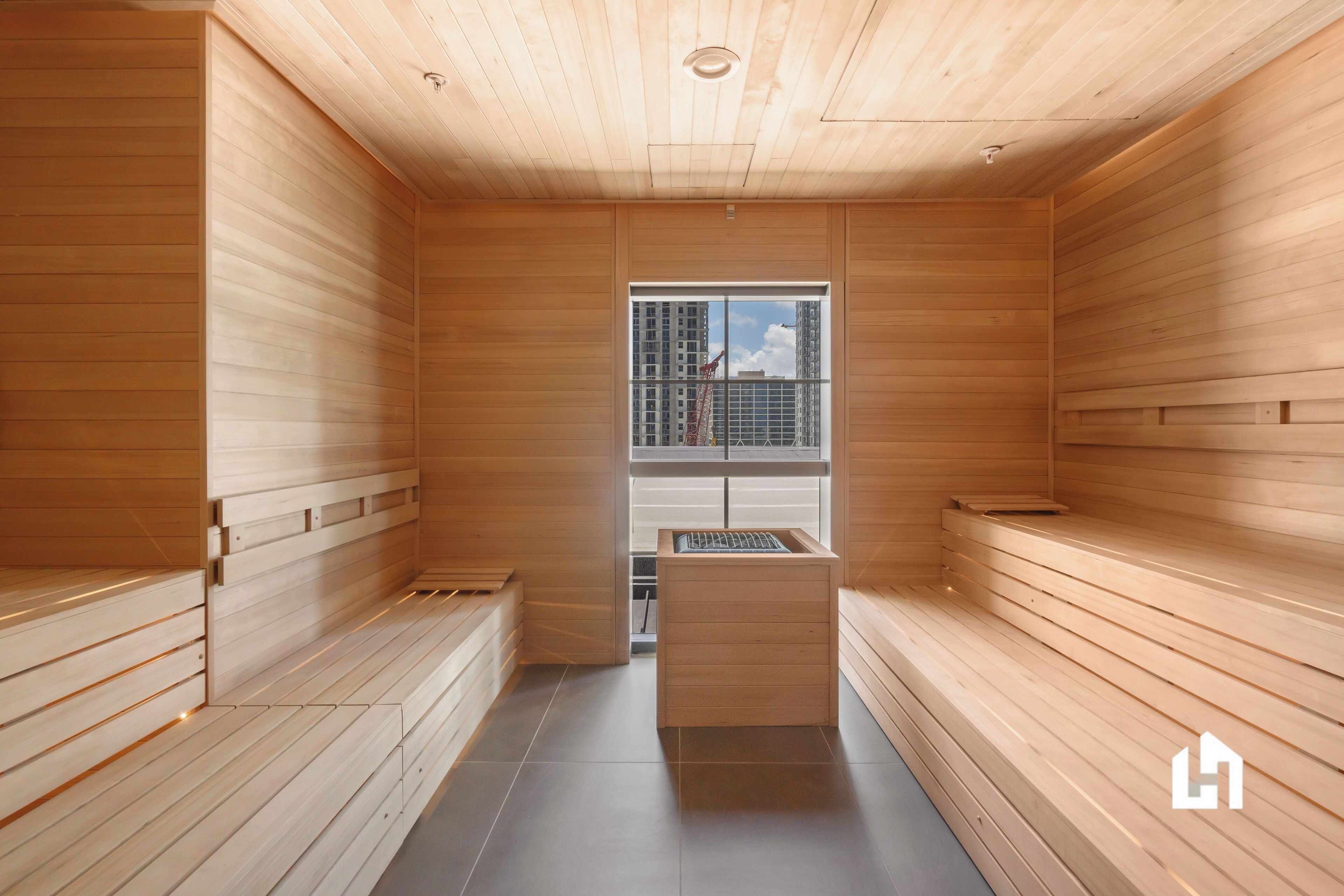 Una sauna amb parets i bancs de fusta, una finestra amb vista a edificis i un petit armari de fusta.