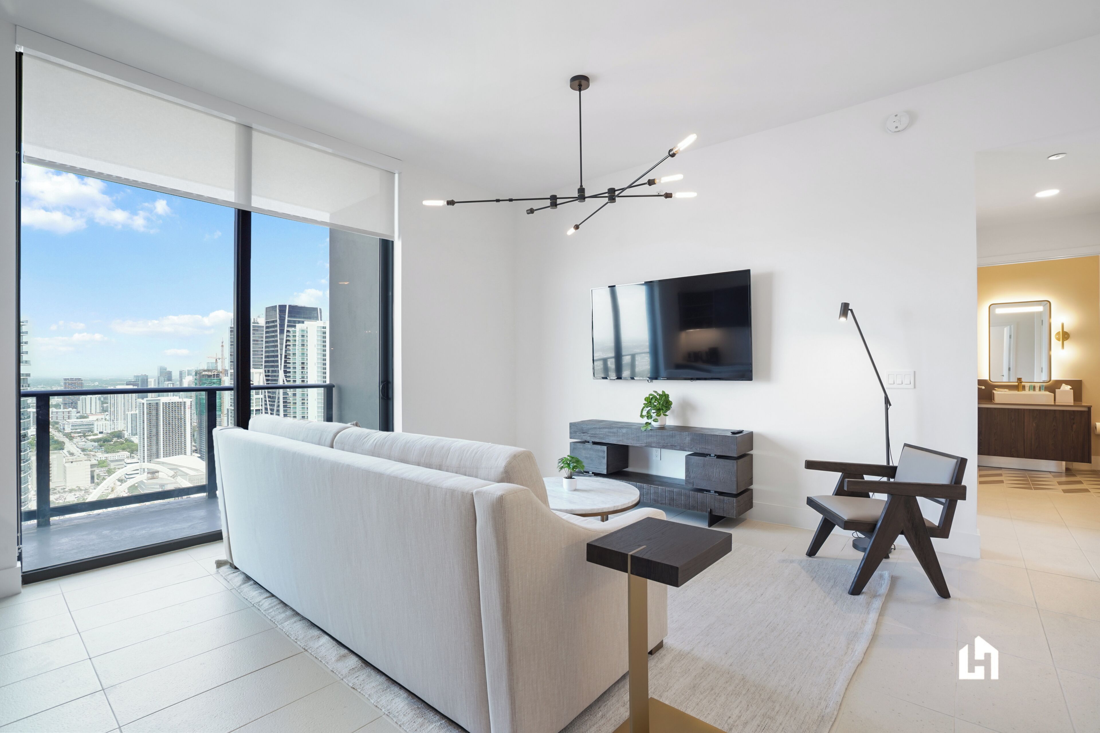 Una sala de estar moderna con un gran ventanal, un sofá, un televisor y una zona de comedor.