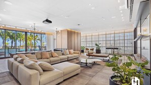 A spacious living area with a large sectional sofa, a coffee table, and a potted plant. - Stylish Apartments with Partial Ocean Views in Downtown (Miami)
