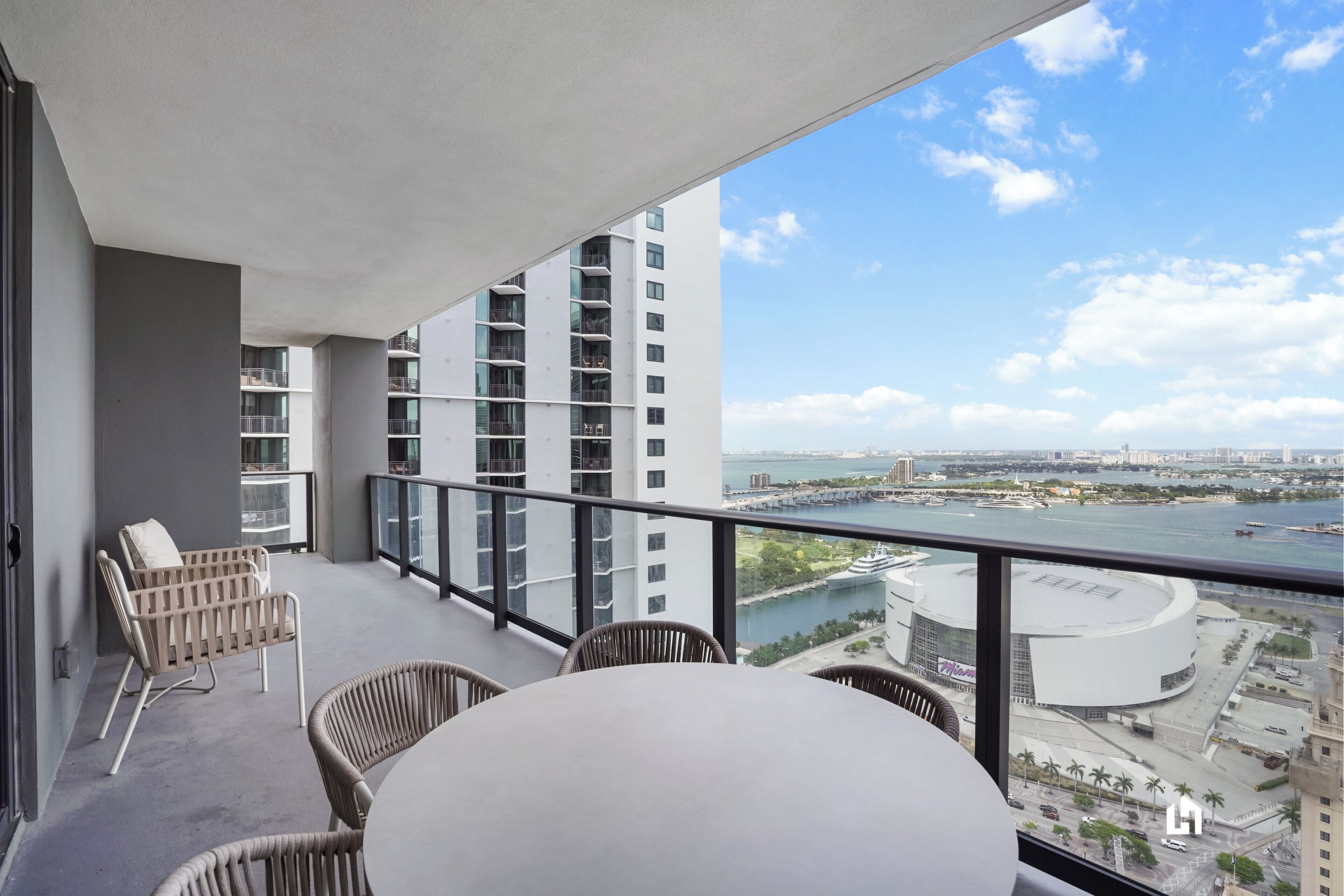 A balcony with wicker furniture and a view of a river and cityscape.