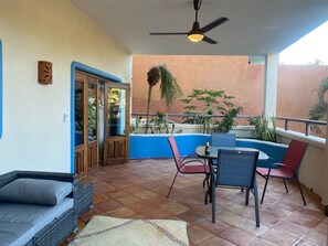 Relax and socialize in this serene outdoor patio, featuring a wicker sofa, small table, and two chairs.