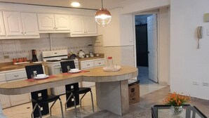 Une cuisine moderne avec des meubles blancs, un îlot central et un coin repas agrémenté de deux chaises noires.