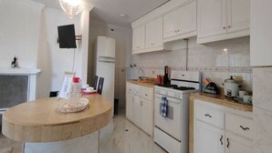 Une cuisine avec des meubles blancs, un îlot central en bois rond, une cuisinière et un four à micro-ondes.