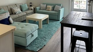 A living room with a sofa, a coffee table, and a dining table. - Relisted!Ocean Blk, Bay&Ocean view, steps to beach best food & bars 2 Full Baths (Ocean City)