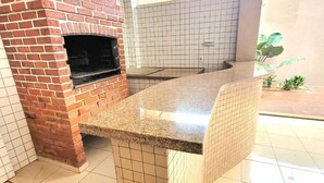 Una cucina con forno in mattoni, zoccolo di piastrelle e pavimento piastrellato.