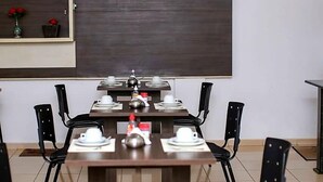 Una sala conferenze con un lungo tavolo apparecchiato per una riunione, dotata di sedie e uno schermo per proiettore.