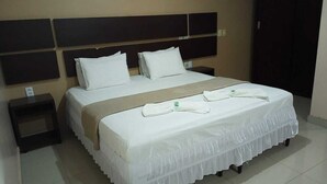 Camera d'albergo con un letto grande, due cuscini, un comodino e una abat-jour.