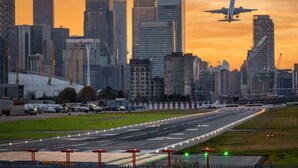 A cityscape with modern buildings and a runway. - Spacious 4-Bedroom Home | Driveway & Garden (Greater London)