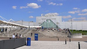 A stadium with a large 'EXCEL' sign, tiered seating, and a clear sky. - Spacious 4-Bedroom Home | Driveway & Garden (Greater London)