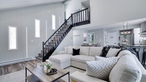 Una sala de estar moderna con una escalera, un sofá y una mesa de centro.
