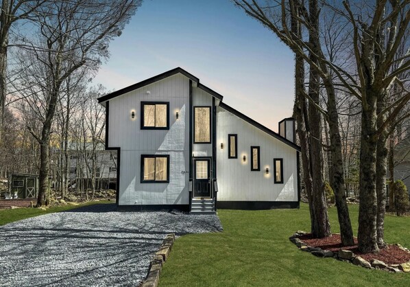 Et moderne hus i to etager med en symmetrisk facade, store vinduer og en central indgang.
