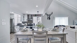 Una cocina moderna con comedor, que presenta una mesa de madera, sillas y una cabeza de venado decorativa en la pared.
