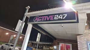 A gas station named 'ACTIVE247' with a clear sign, a canopy, and a brick building in the background.