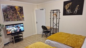 A hotel room with two beds, a TV, a chair, and artwork on the walls.