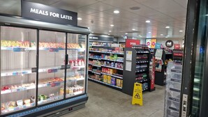 A grocery store with refrigerated sections, shelves stocked with various products, and signs indicating special offers.