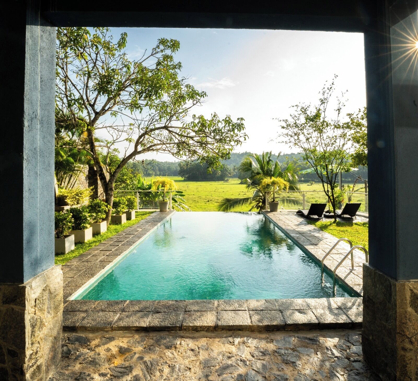 A swimming pool with a view of a green landscape and trees.