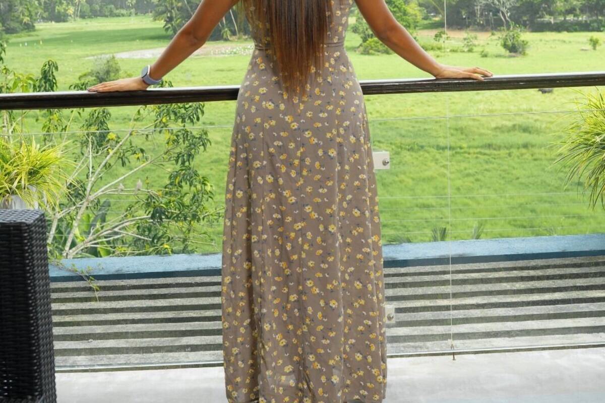 A woman standing on a balcony with a view of a green landscape.
