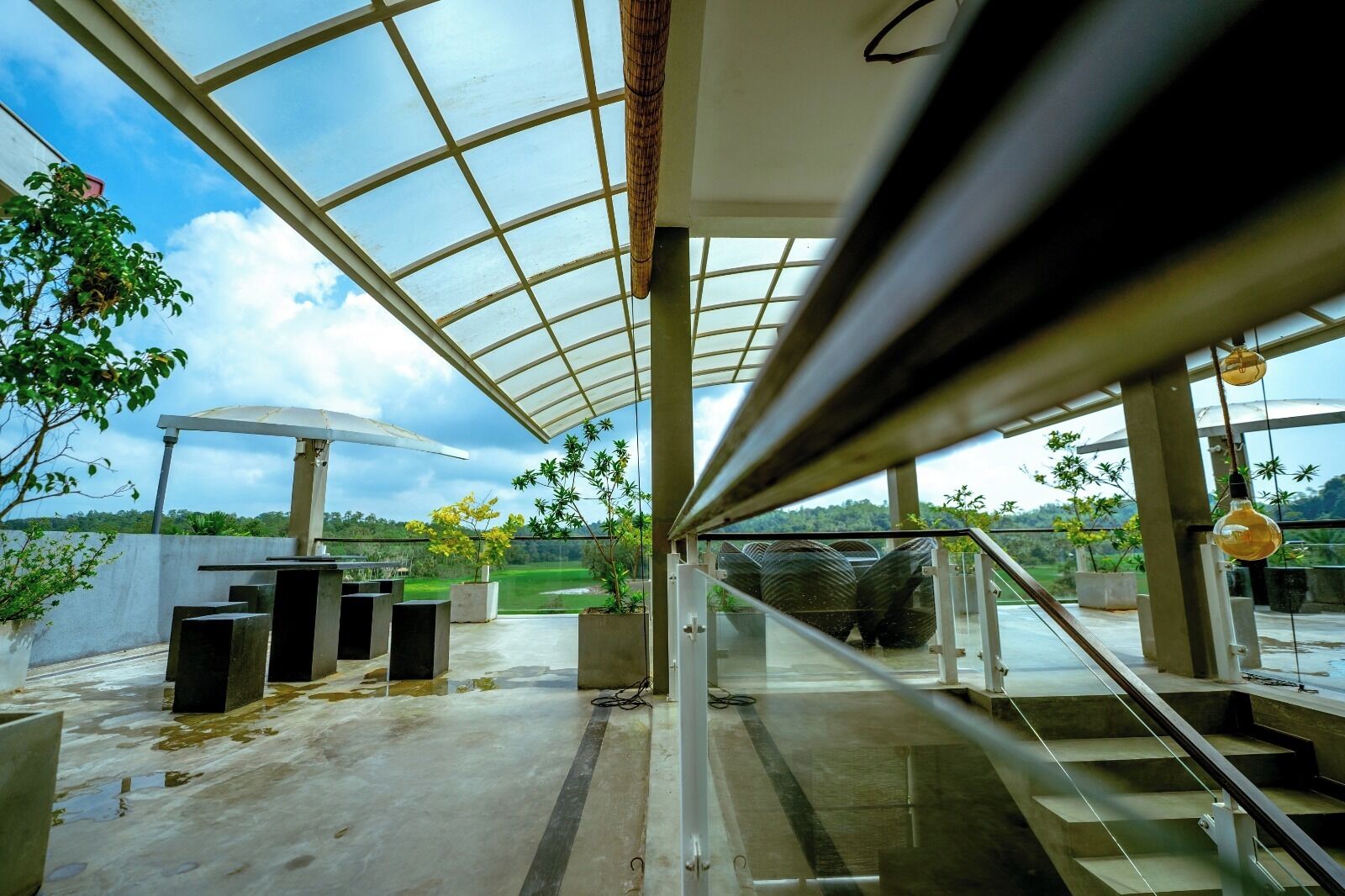 A modern interior with a glass ceiling, concrete flooring, and a staircase leading to an outdoor area with greenery.