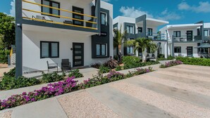 Un edificio moderno con balcón, mobiliario exterior y un jardín cuidado.