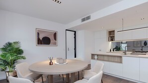 A modern kitchen with white cabinetry, a round dining table with four chairs, and a potted plant.