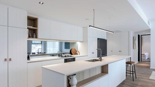 A modern kitchen with white cabinetry, a central island, and a built-in stove.