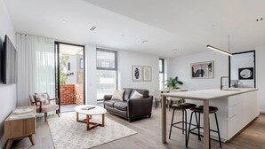 A modern living room with a sofa, coffee table, and a dining area with a kitchen island.