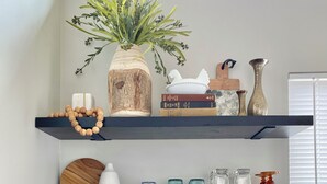 A kitchen with three shelves, a coffee maker, and various kitchen items.