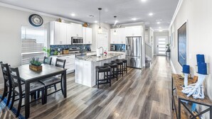 A modern kitchen with a central island, white cabinetry, and a stainless steel refrigerator. - PrivateHeatedPool!GameRoom!Sleeps11! (Corpus Christi)