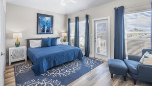 A bedroom with a large bed, a ceiling fan, a nightstand with a lamp, a chair, and a view of the outside through a window with blinds. - PrivateHeatedPool!GameRoom!Sleeps11! (Corpus Christi)