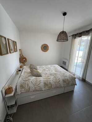 A bedroom with a bed, bedside table, lamp, and wall decorations. - Comfortable apartment in new residence (propriano)
