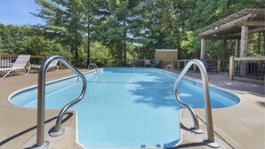 A swimming pool with metal railings, surrounded by trees and a wooden pergola. - New Room by Silver Dollar City + Shuttle + Pool (Branson)
