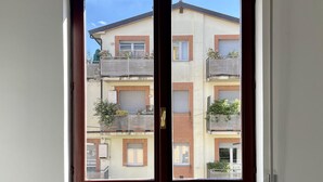 Una ventana con vistas a un edificio de varios pisos con balcones y un radiador debajo.