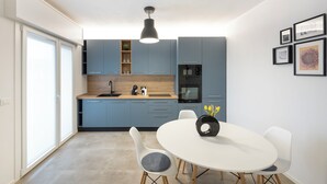 Una cocina moderna con armarios azules, una mesa de comedor blanca y una lámpara colgante.